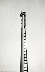 168860 Afbeelding van het aanbrengen van een ijzeren paalmanchet op een bovenleidingsmast ten behoeve van de ...